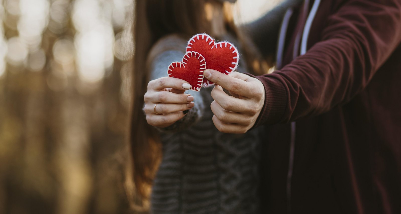 A pair of lovers holding two red hearts in hand for valentines day